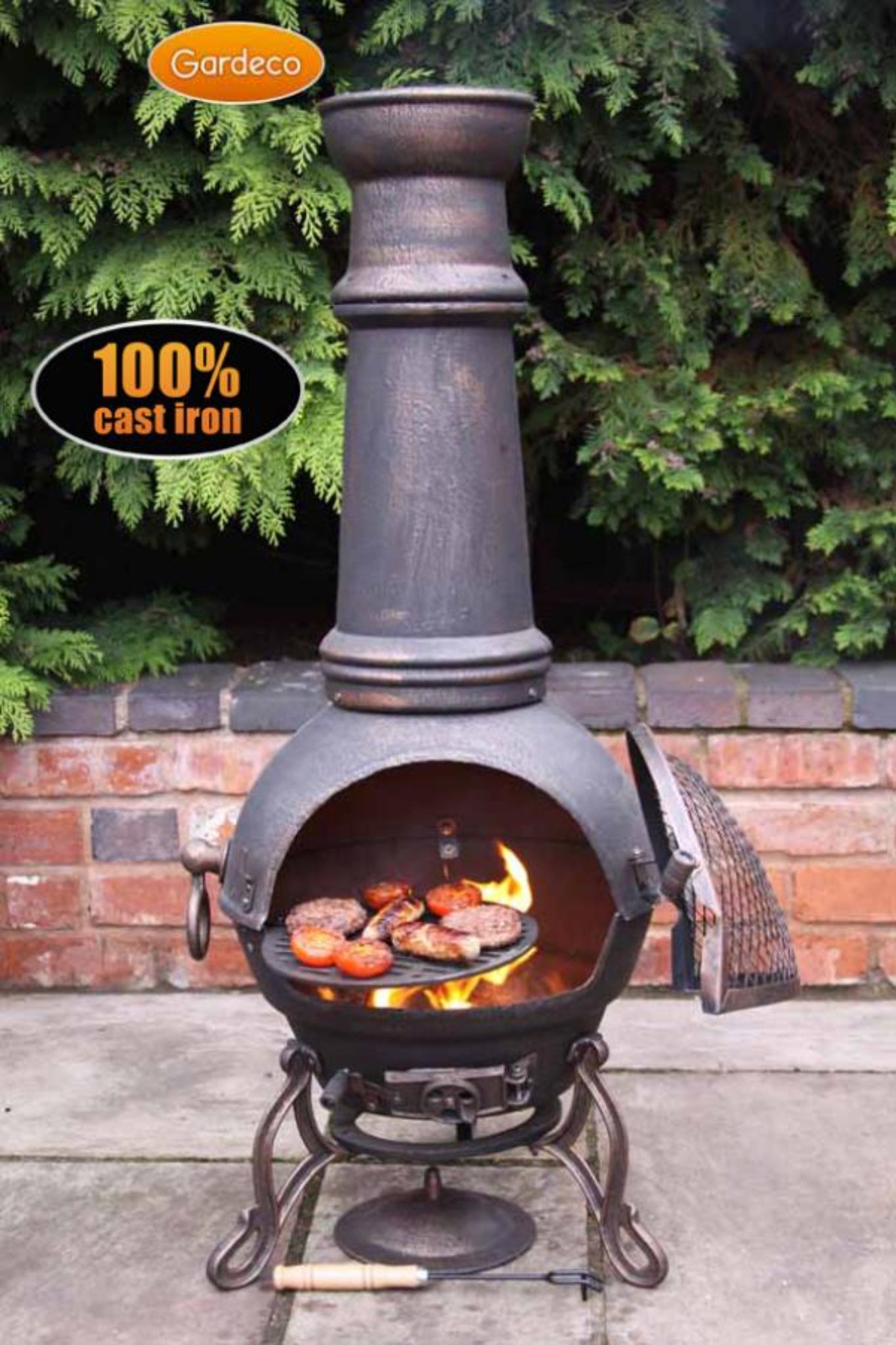 Cast iron chiminea with grill on a patio, surrounded by greenery.