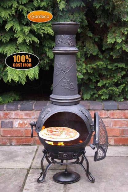 Cast iron chiminea with pizza inside, branded 'Gardeco', on a patio with greenery in the background.