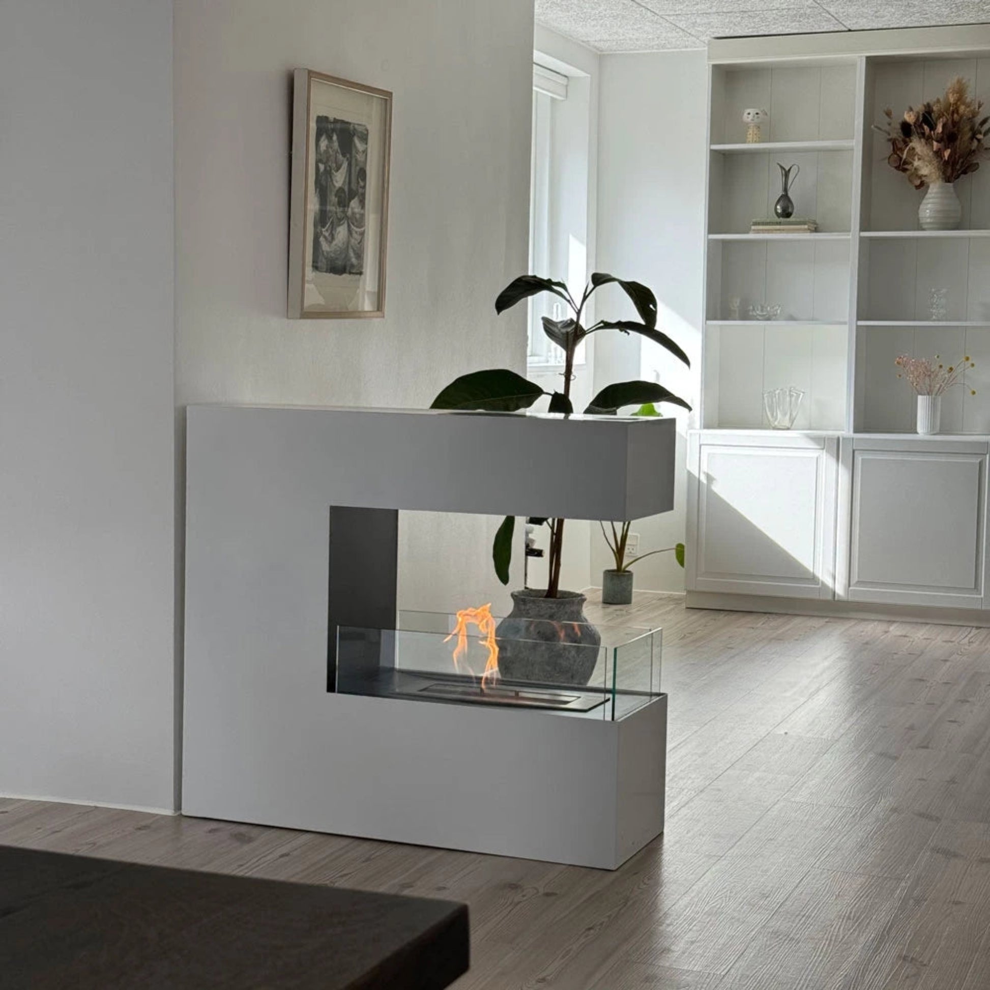 Modern white fireplace with glass front in a living room setting.