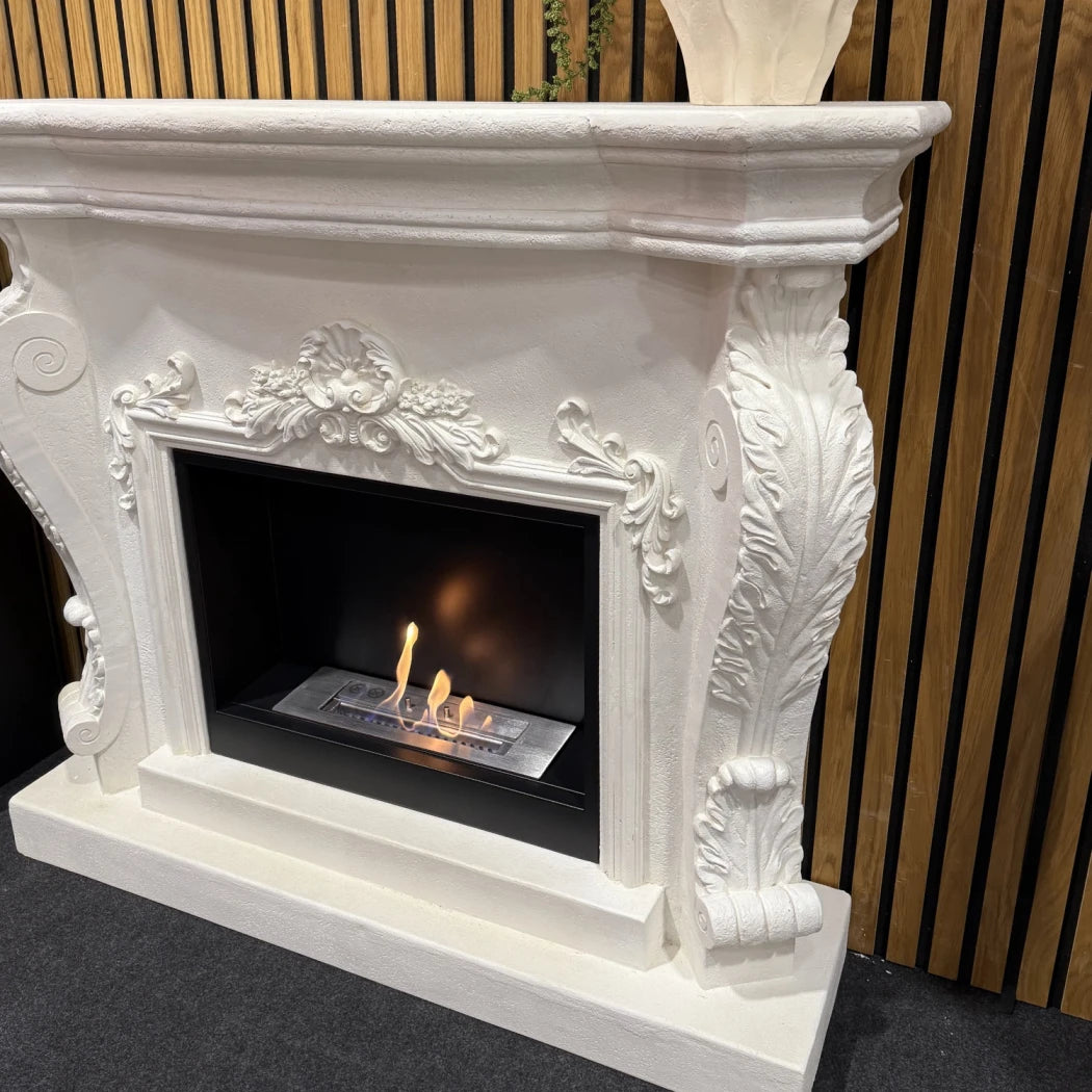 Decorative white fireplace with intricate designs against a wooden slat background