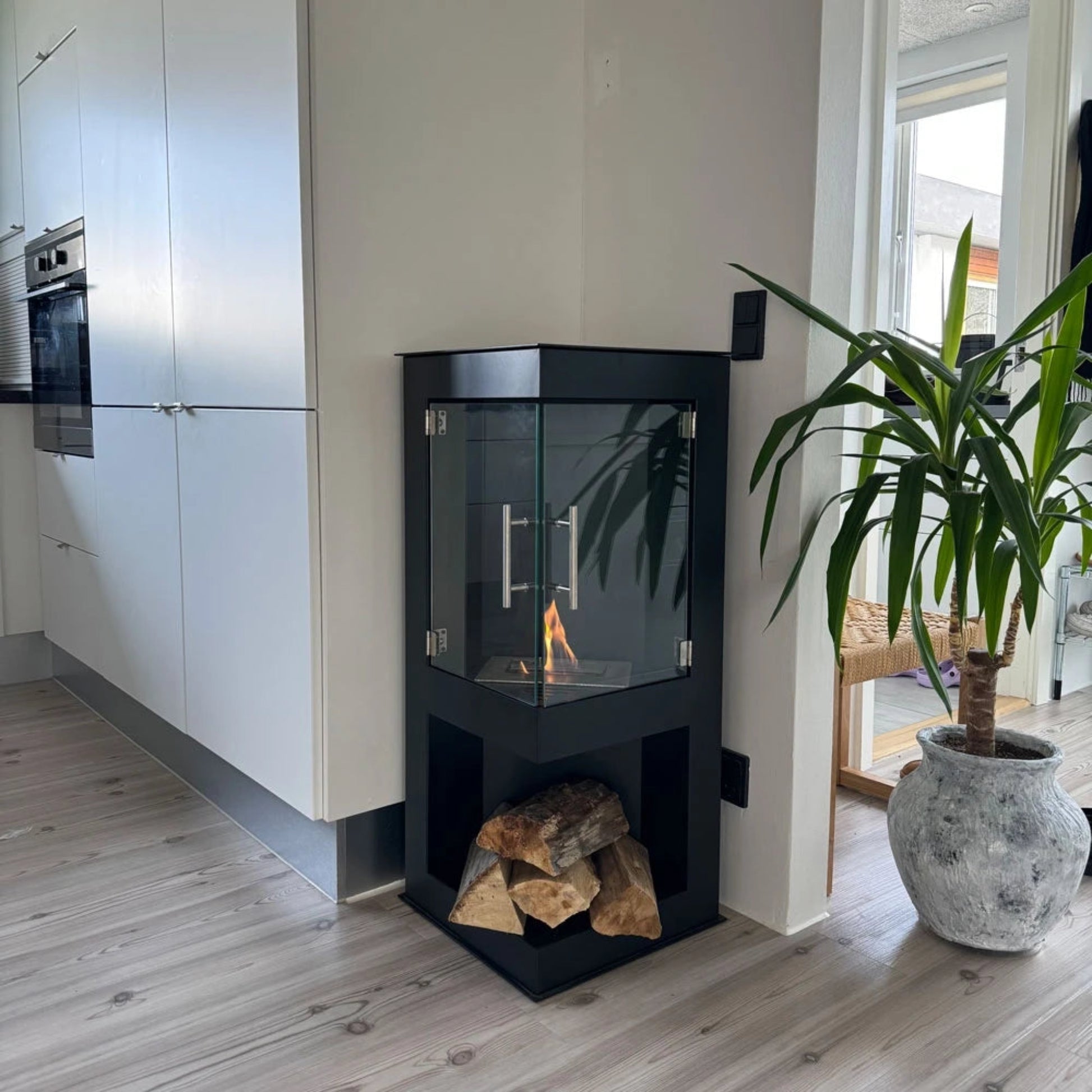 Modern kitchen with a black freestanding fireplace and potted plant.