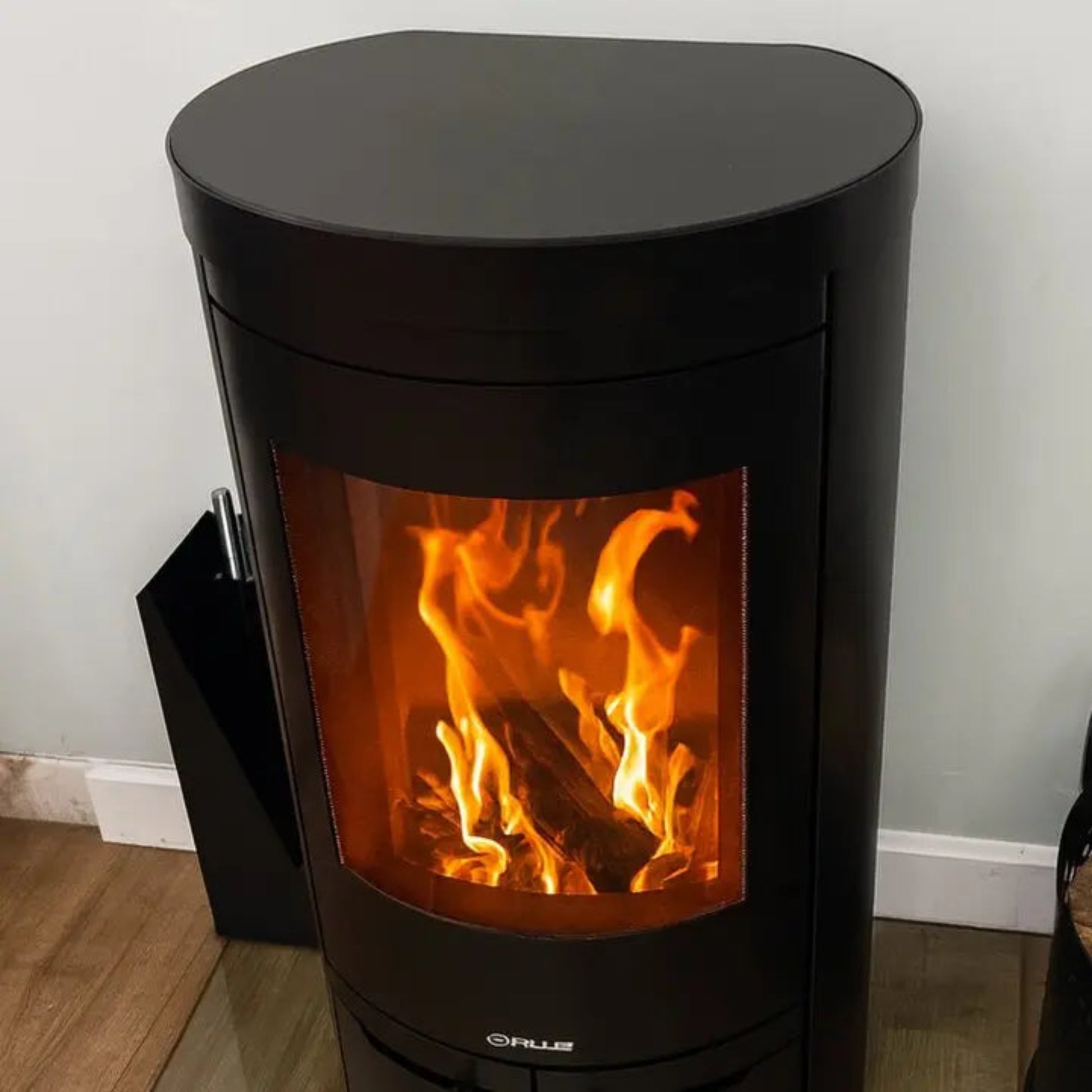 Opus Aria D Hot Top Wood-burning stove with flames inside, on a wooden floor.