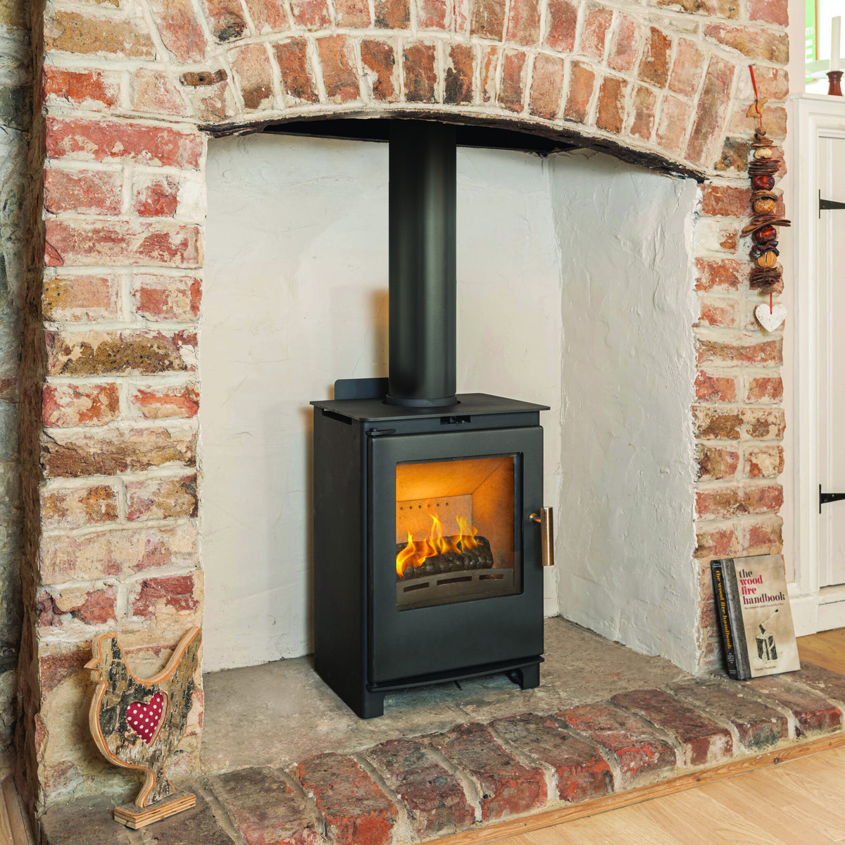 Beltane Brue wood-burning stove installed in a rustic brick fireplace