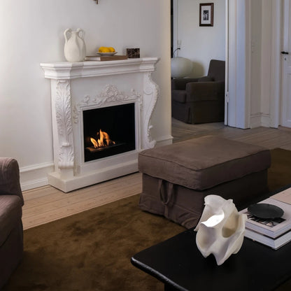 Living room with a fireplace, ottoman, and coffee table.