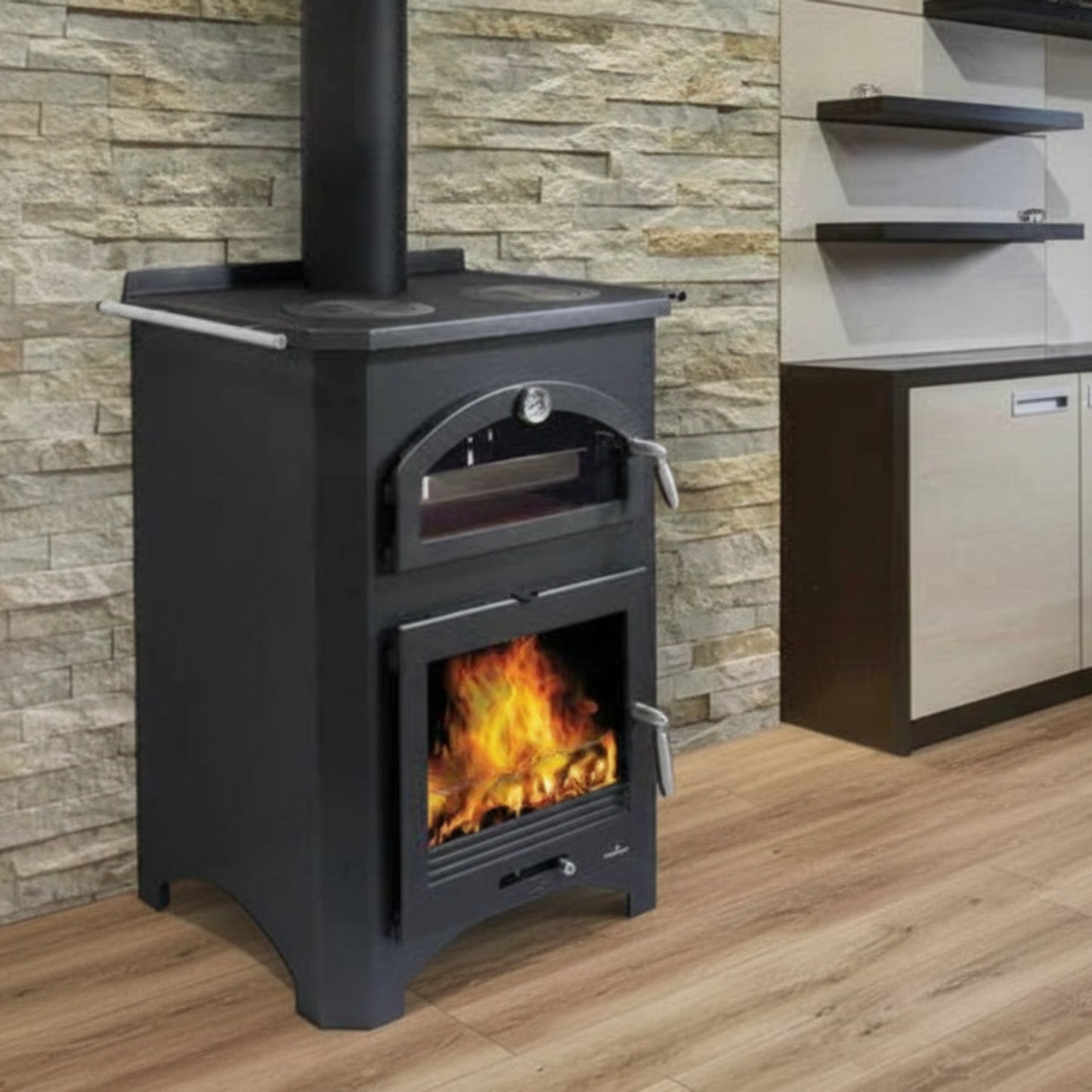 Black  Bronpi Monza wood stove with fire burning inside, against a stone wall.