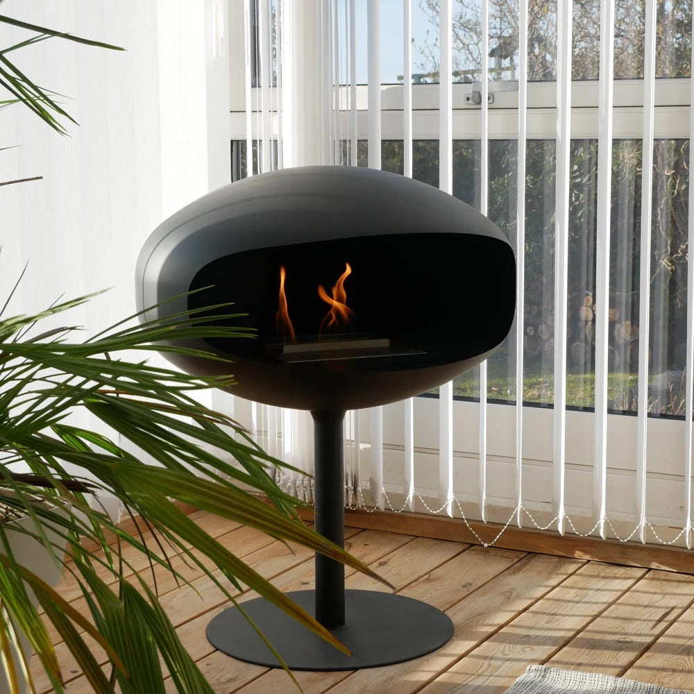 Cocoon Pedestal Freestanding Bioethanol Fireplace - Black Black Base in room with wooden floor and green plant