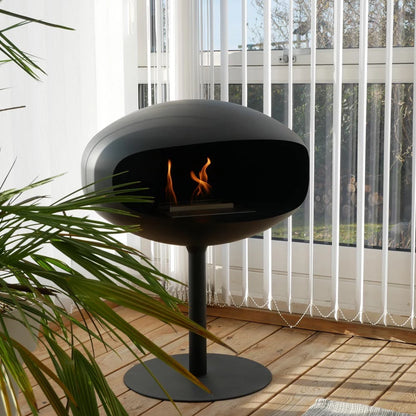 Cocoon Pedestal Freestanding Bioethanol Fireplace - Black Black Base in room with wooden floor and green plant