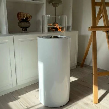 Modern white freestanding fireplace in a room with wooden floor and white cabinets.
