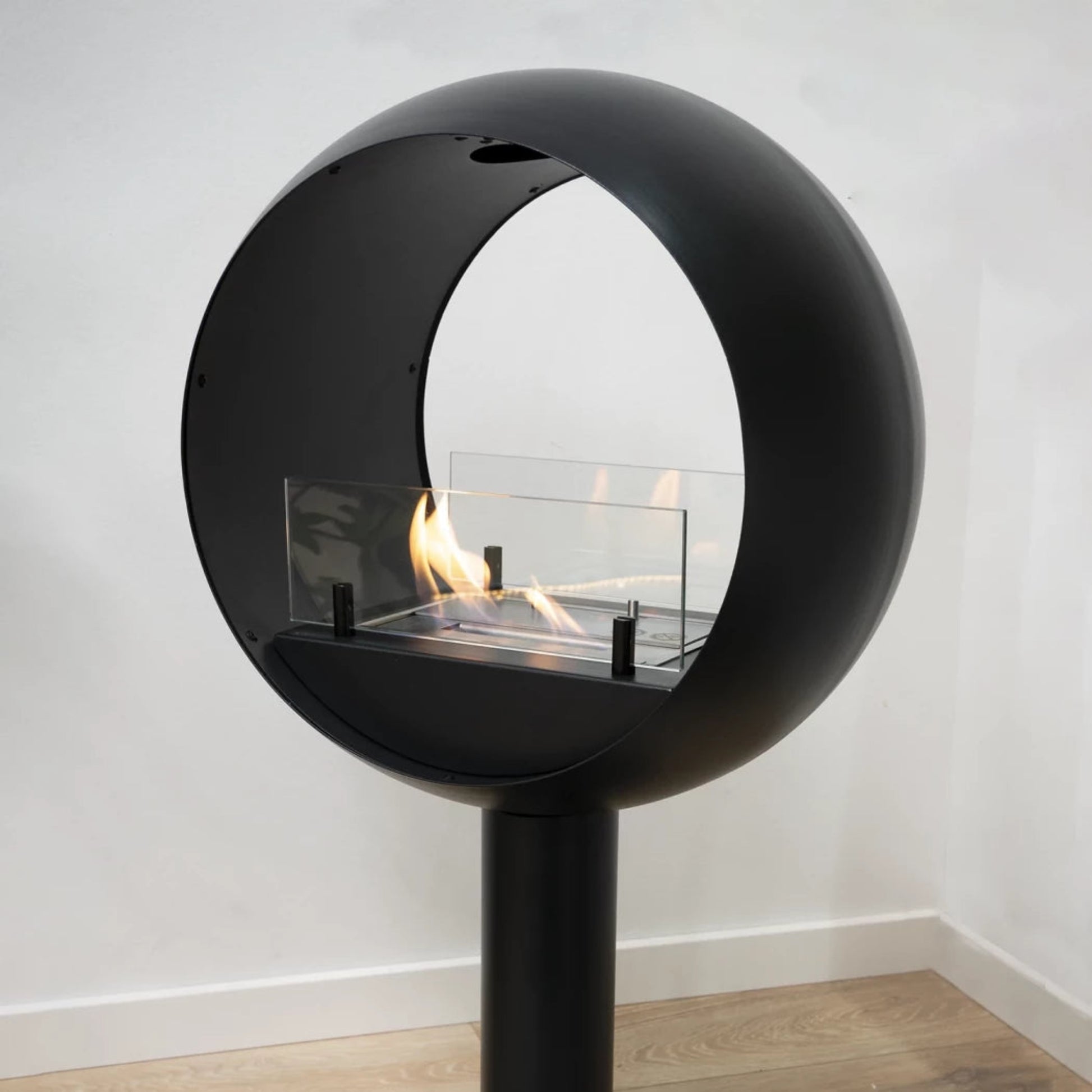 Modern black freestanding fireplace with glass protection on a white background