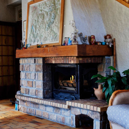 Brick fireplace with ScandiFlames 40cm Bioethanol Fire Grate under a wooden mantel and various items in a room.