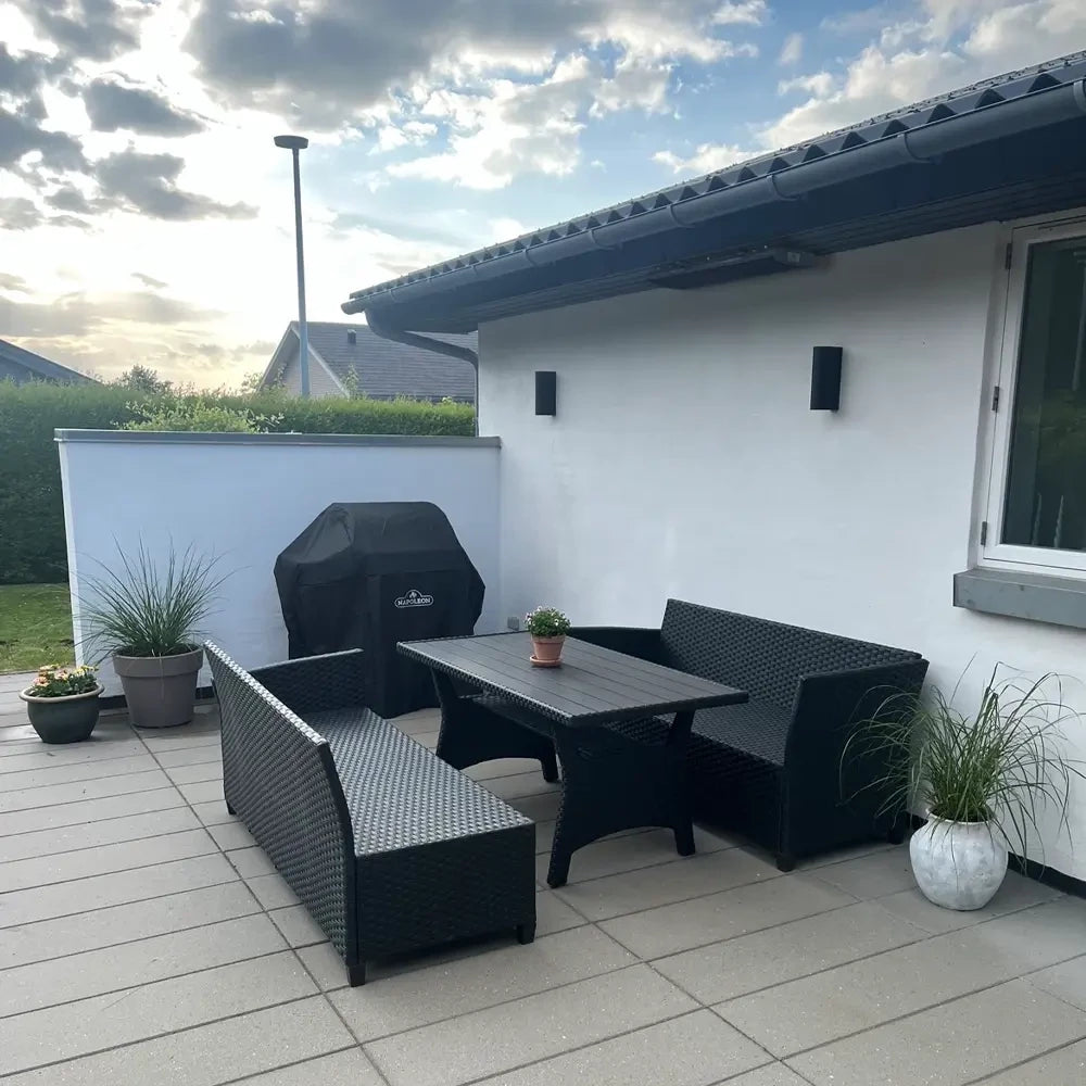 Outdoor patio area with black patio furniture set against a white house.