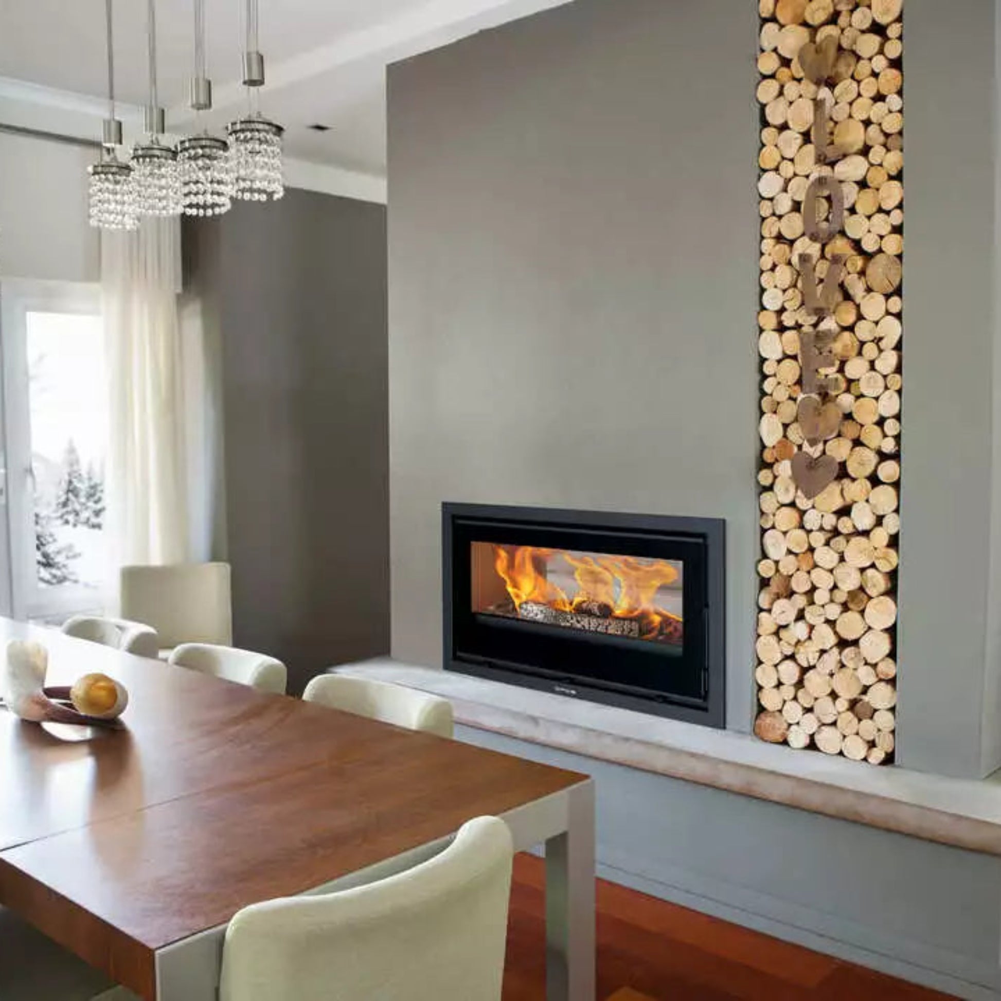 Opus Octave 90i Double sided stove in dining room dividing wall with vertical log store next to it and a kitchen table with white upholstered chairs.