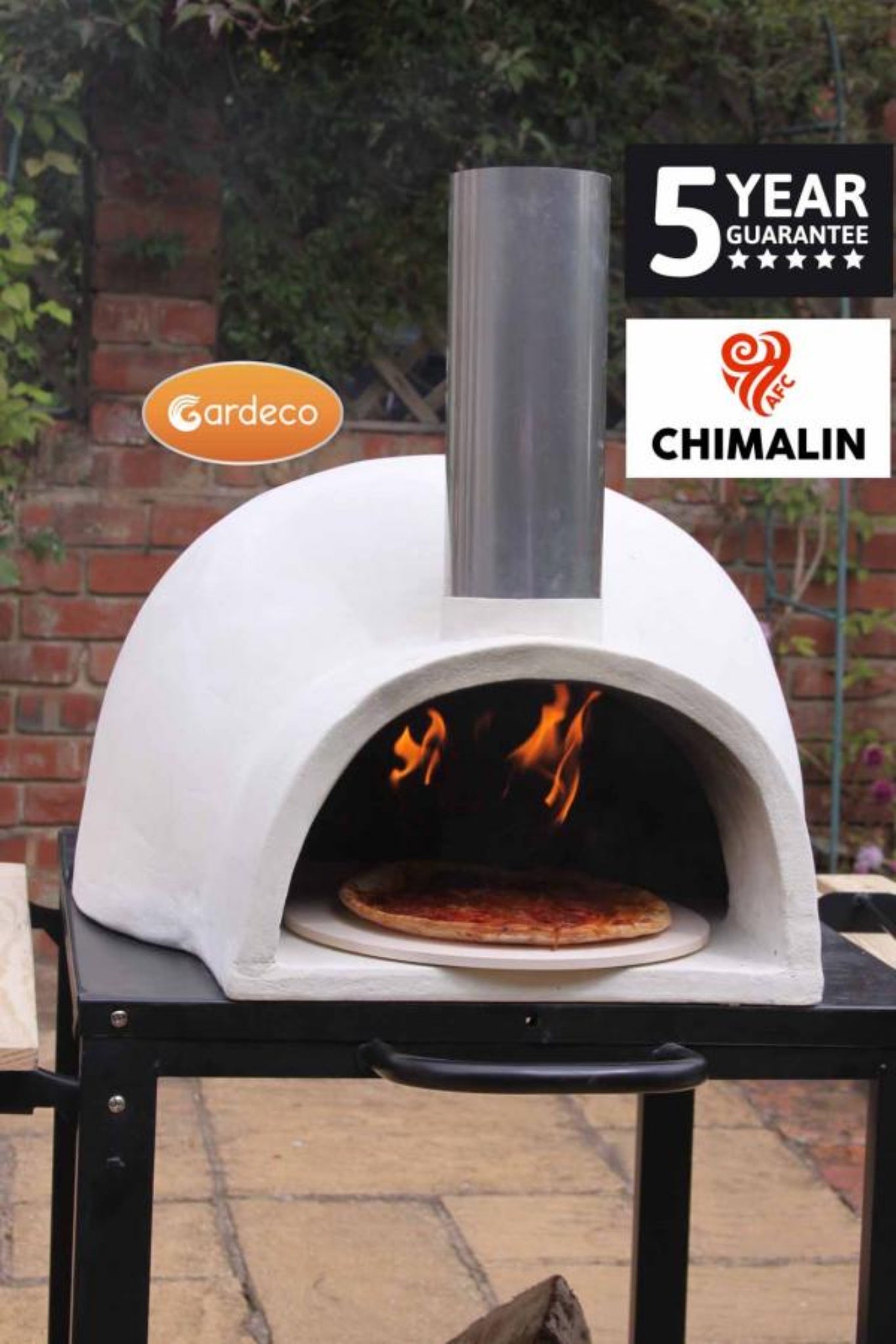 White outdoor pizza oven with fire inside, on a brick patio with 'Gardeco' and 'Chimalin' branding.