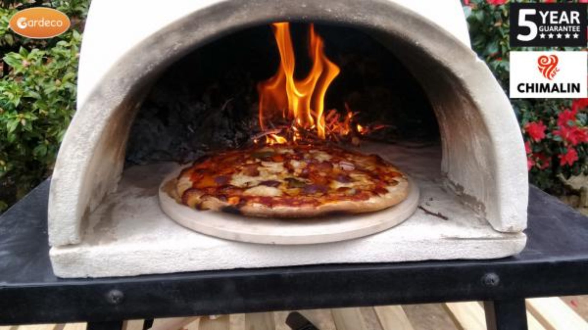 Pizza being cooked in a stone oven with flames, surrounded by greenery and a Chimalin logo.