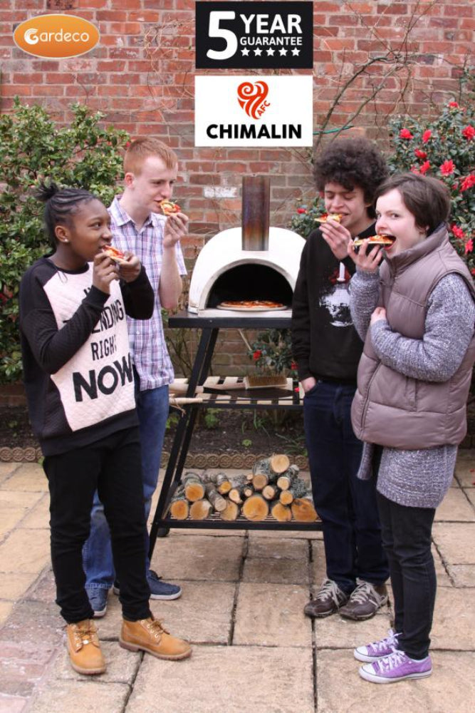 Four people enjoying pizza around a portable outdoor oven with 'Chimalin' branding.