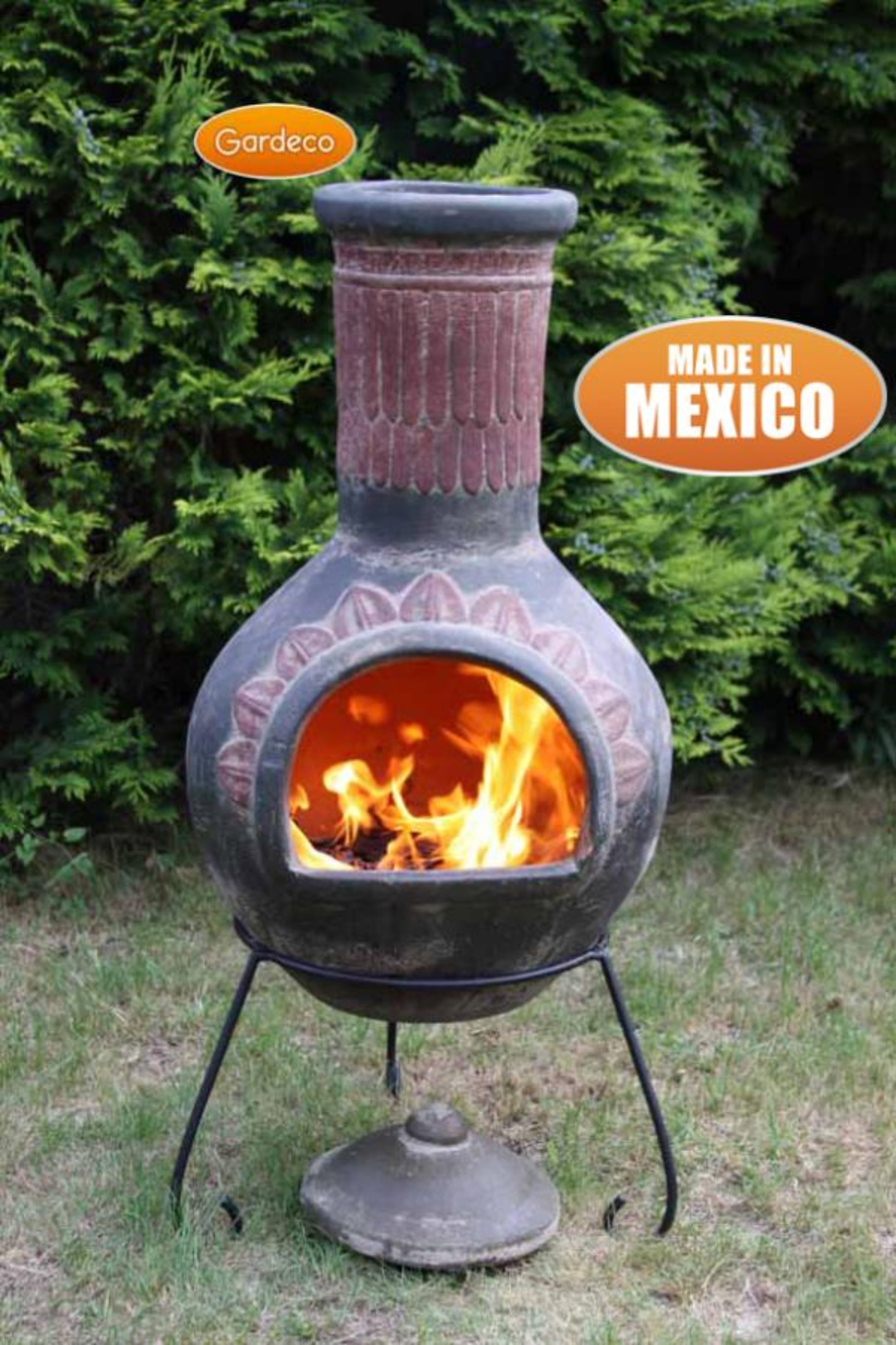 Gardenia chiminea with flames inside, set against a green bush background.