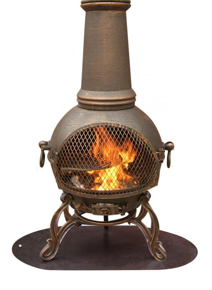 A cast iron ball chaise fireplace with a visible fire inside, shown on a plain white background. It features a tall chimney, a front mesh fire guard, ornate legs, and an oval base plate.