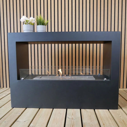 Modern outdoor ethanol fireplace on a wooden deck with plants on the mantel.