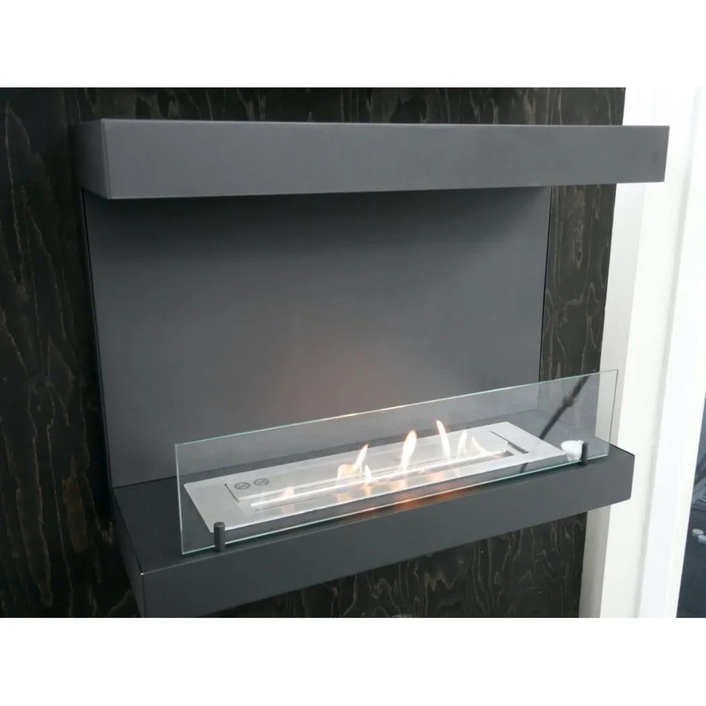 Modern ethanol fireplace with glass panel on a dark background